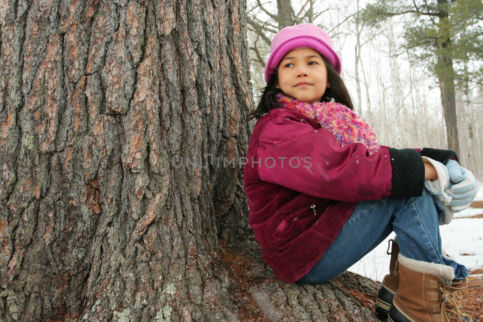 Nine year old girl enjoying sitting under tree in winter