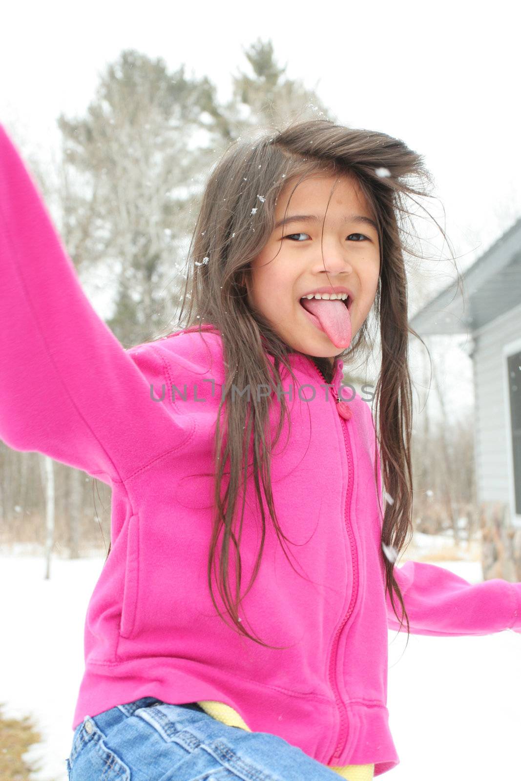 Child sticking out tongue while playing outdoors in winter