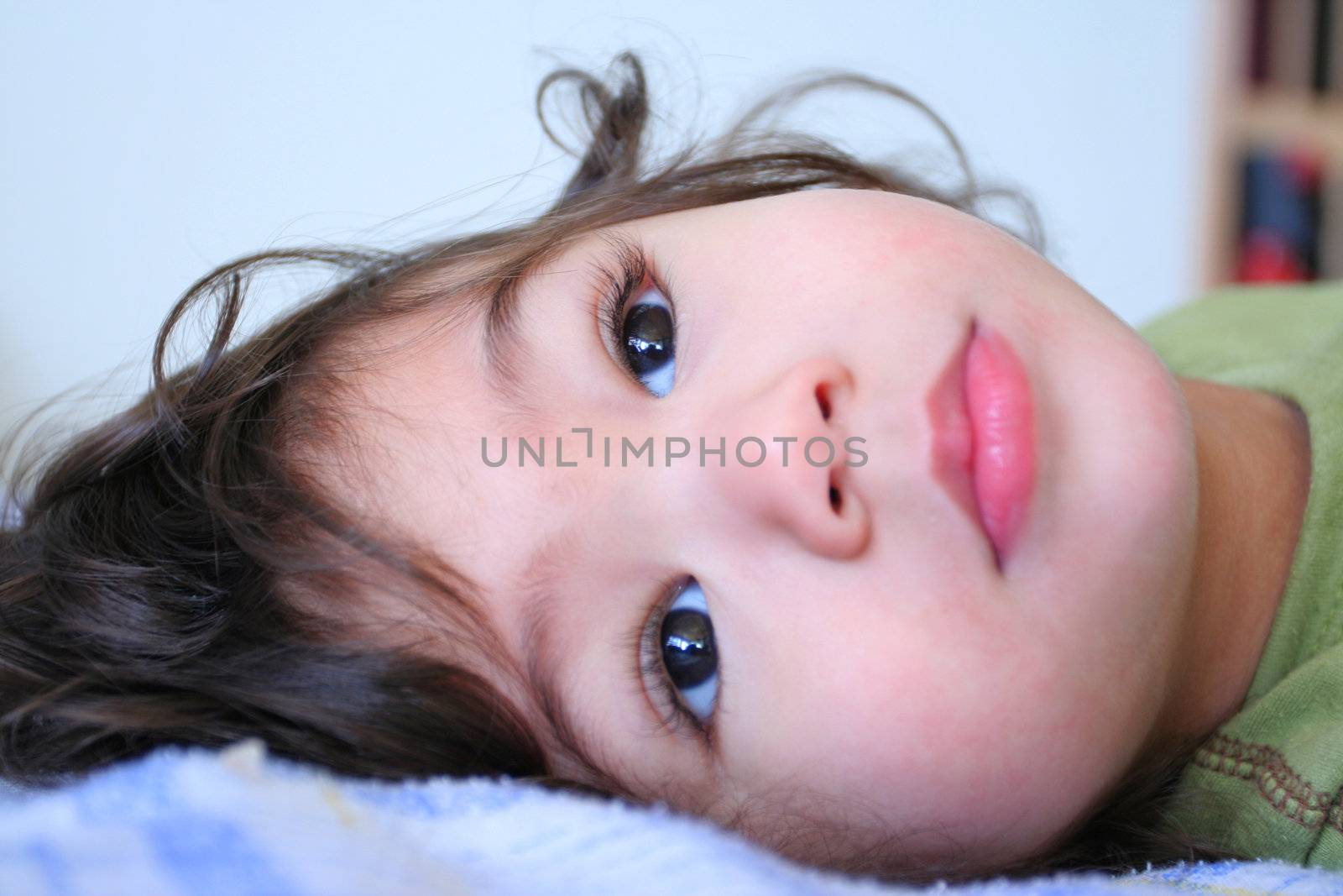 Sweet quiet toddler boy lying down looking gently around. Part Scandinavian, Thai background