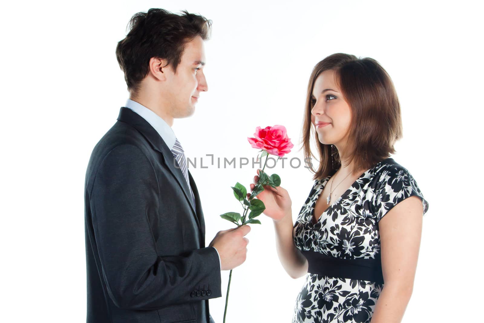 A young man gives a beautiful young woman, a flower in honor of the holiday