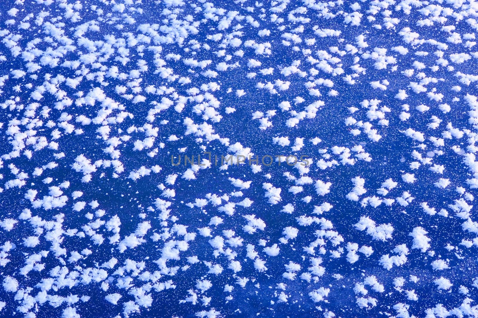 Fragment of frozen surface with the rime in the form of randomly placed snowflakes