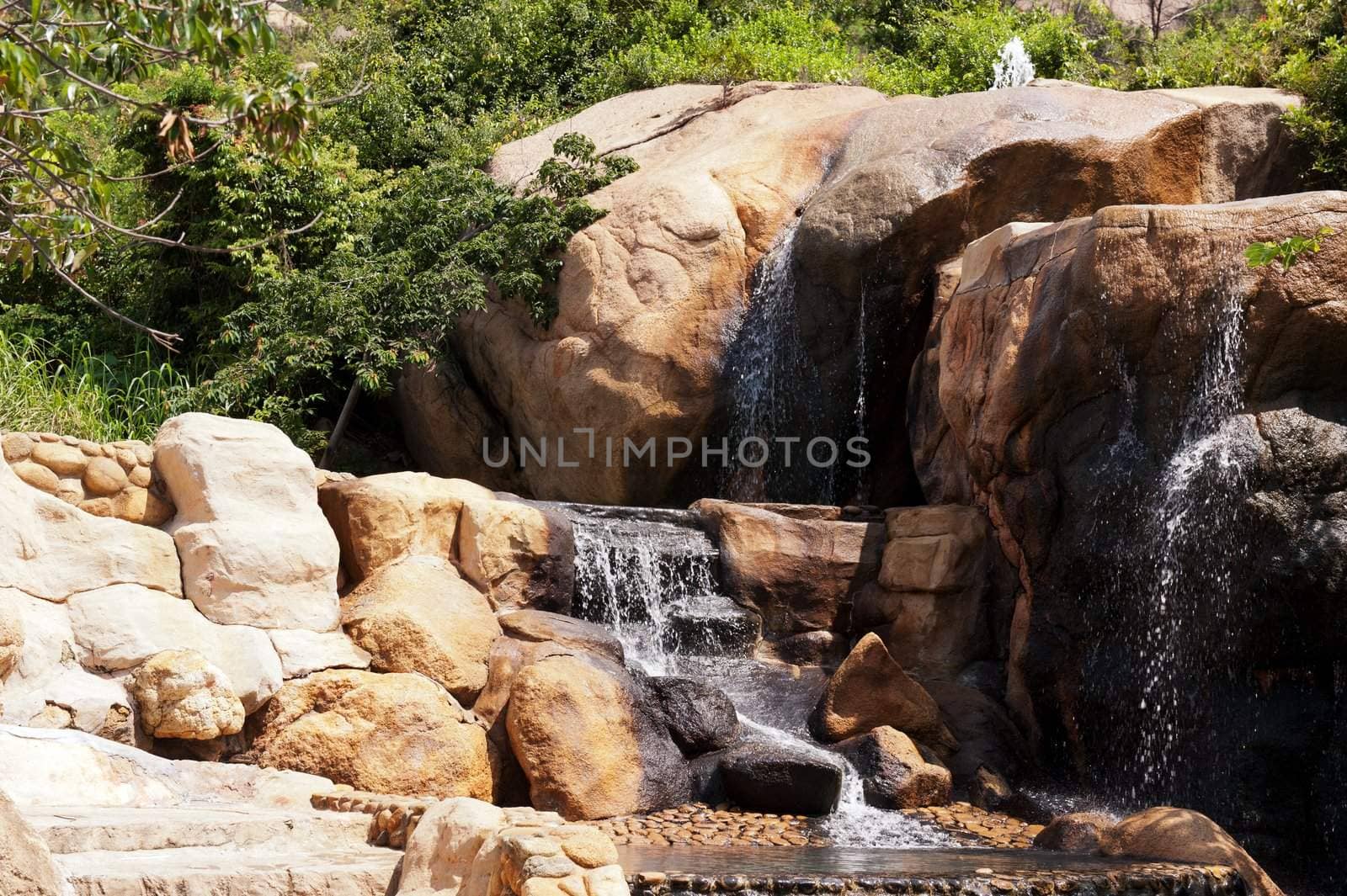 Waterfall in the garden with stones and trees