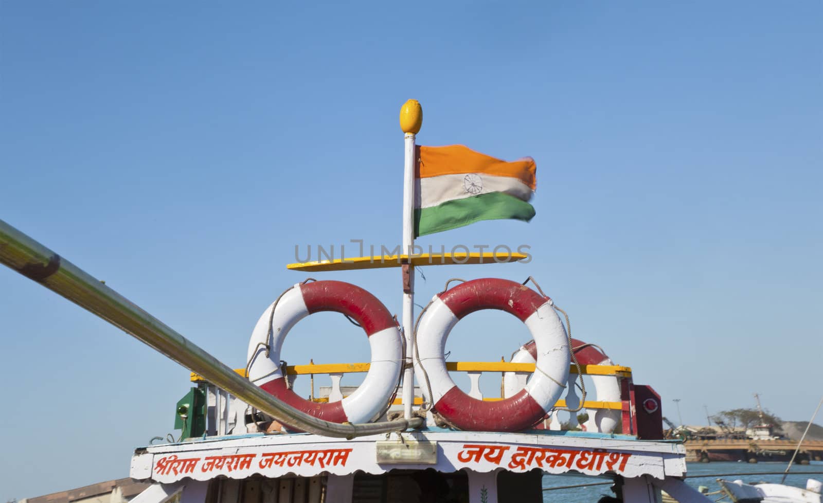 Dwarka Roadtrip. Shot taken on the boat at Bet Dwarka of handrail for passengers to grab and Indian flag blowing in the breeze having a hand drawn Catherine wheel motif