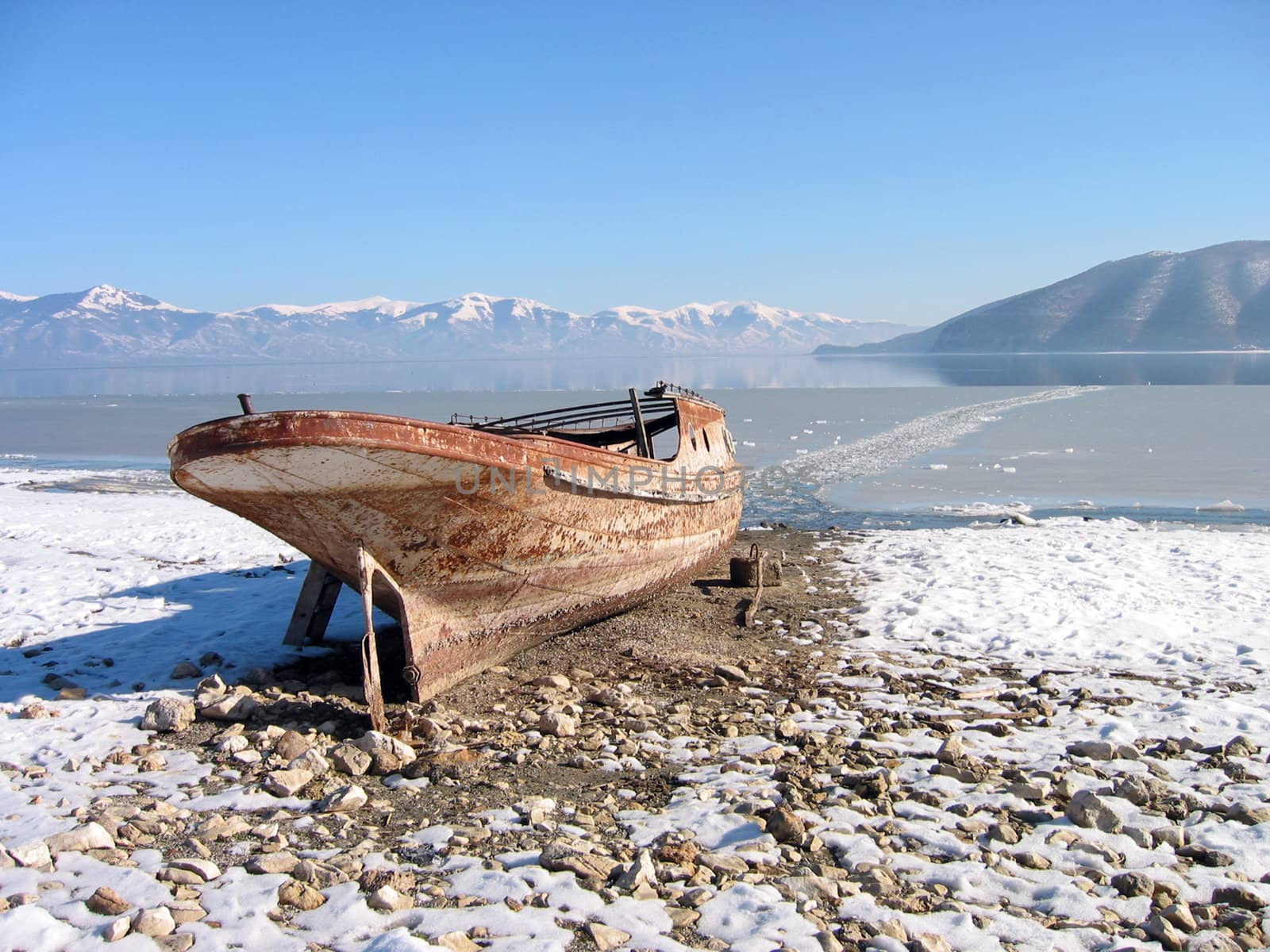 Old lonely boat abandoned at snowy coast,lake prespa, macedonia