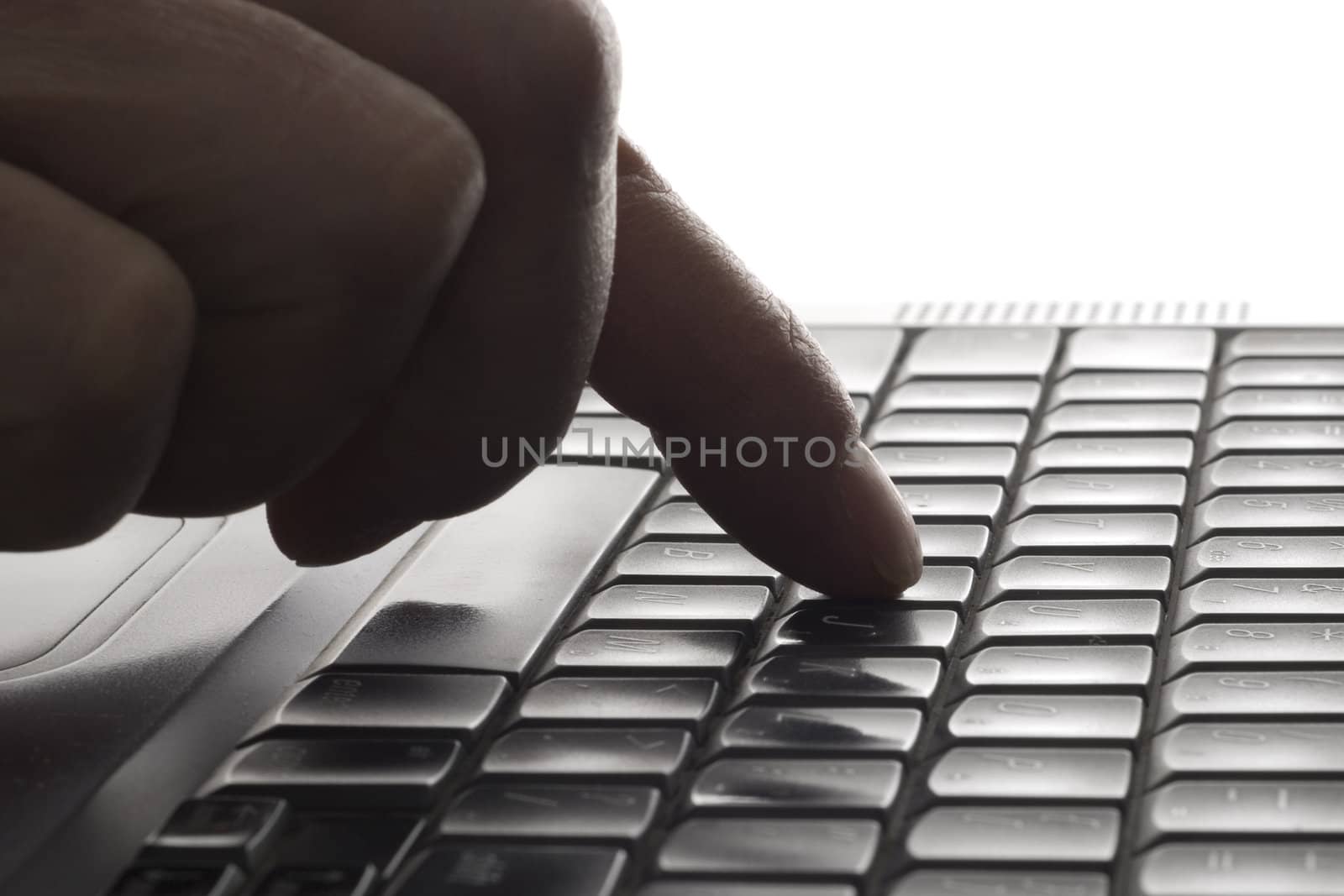Selective focus on the index finger hitting the keyboard of a laptop.