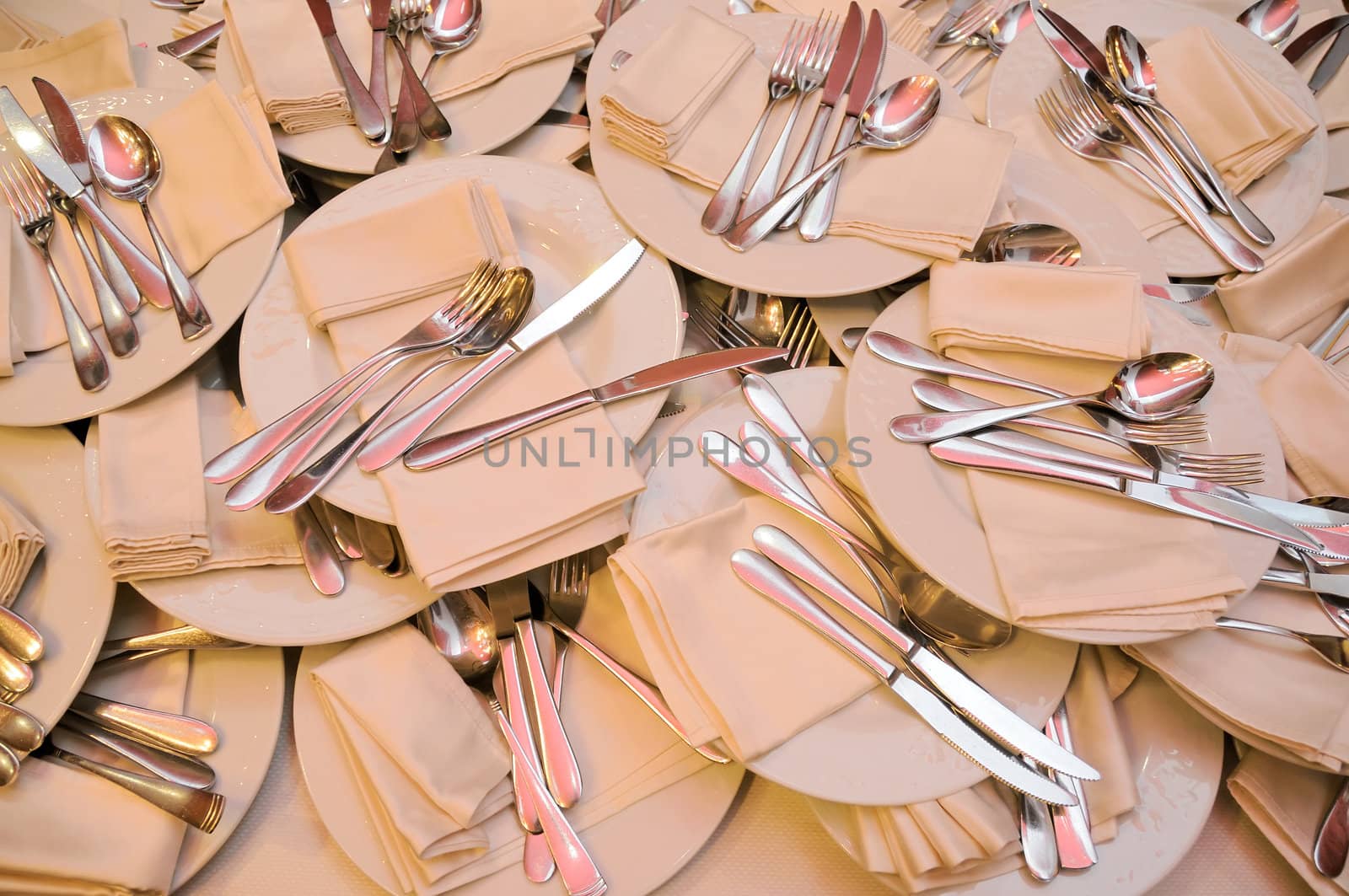 The heap of plates, steel forks, knifes, spoon and napkins