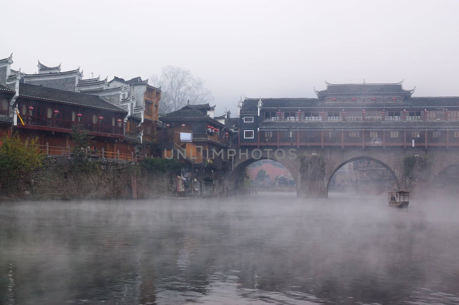 China river landscape with boat, bridge and ancient building in Fenghuang county, Hunan province, China