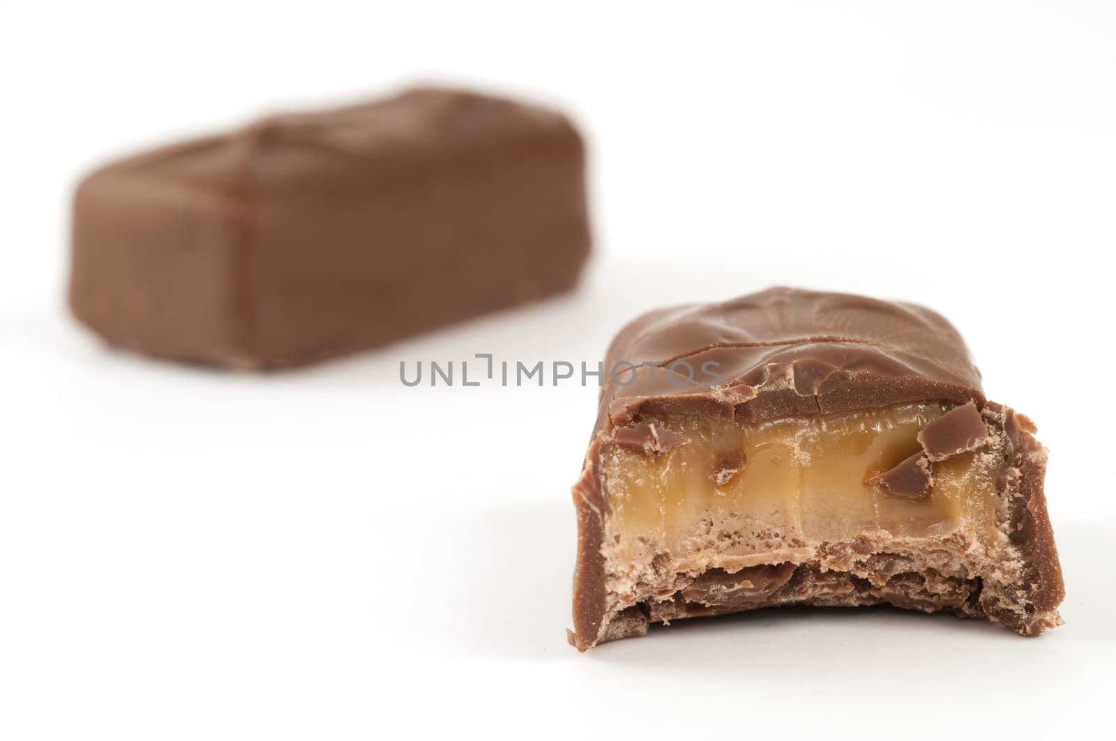 Selective focus on the bite out of a small chocolate bar with another chocolate bar in the background with both isolated on white background