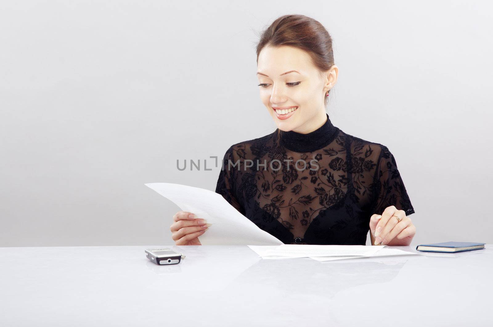 Smiling lady sitting at the table and working with documents