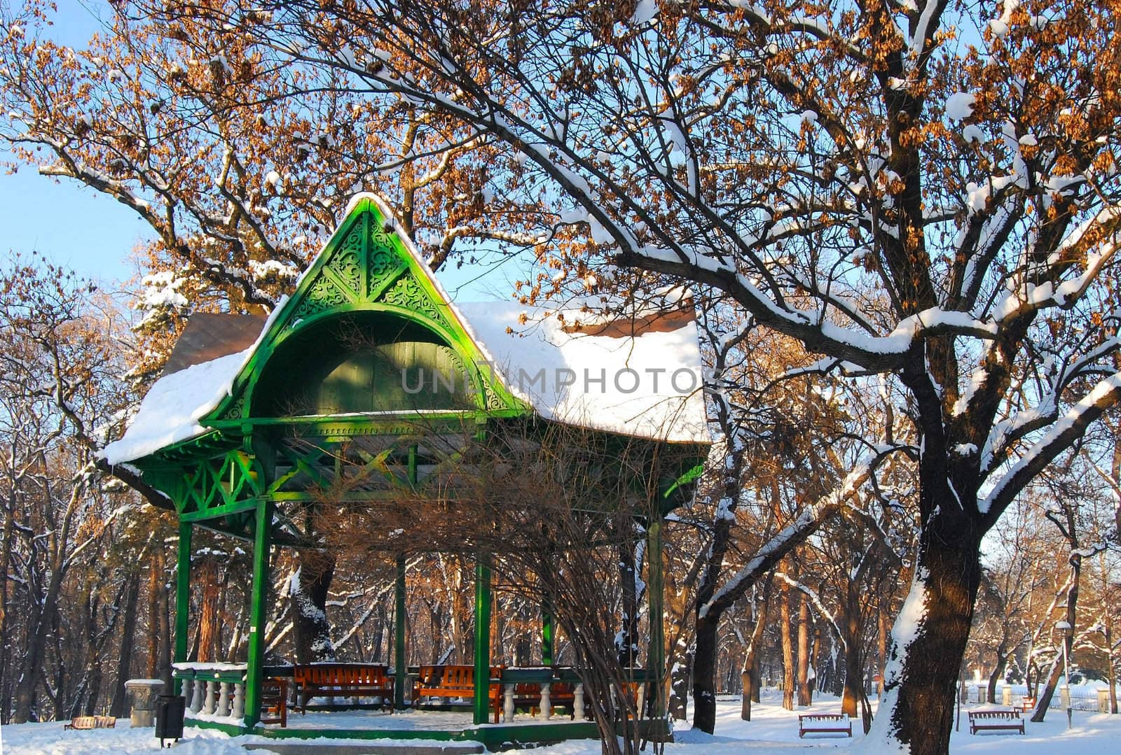 Old green wooden park arbour in winter