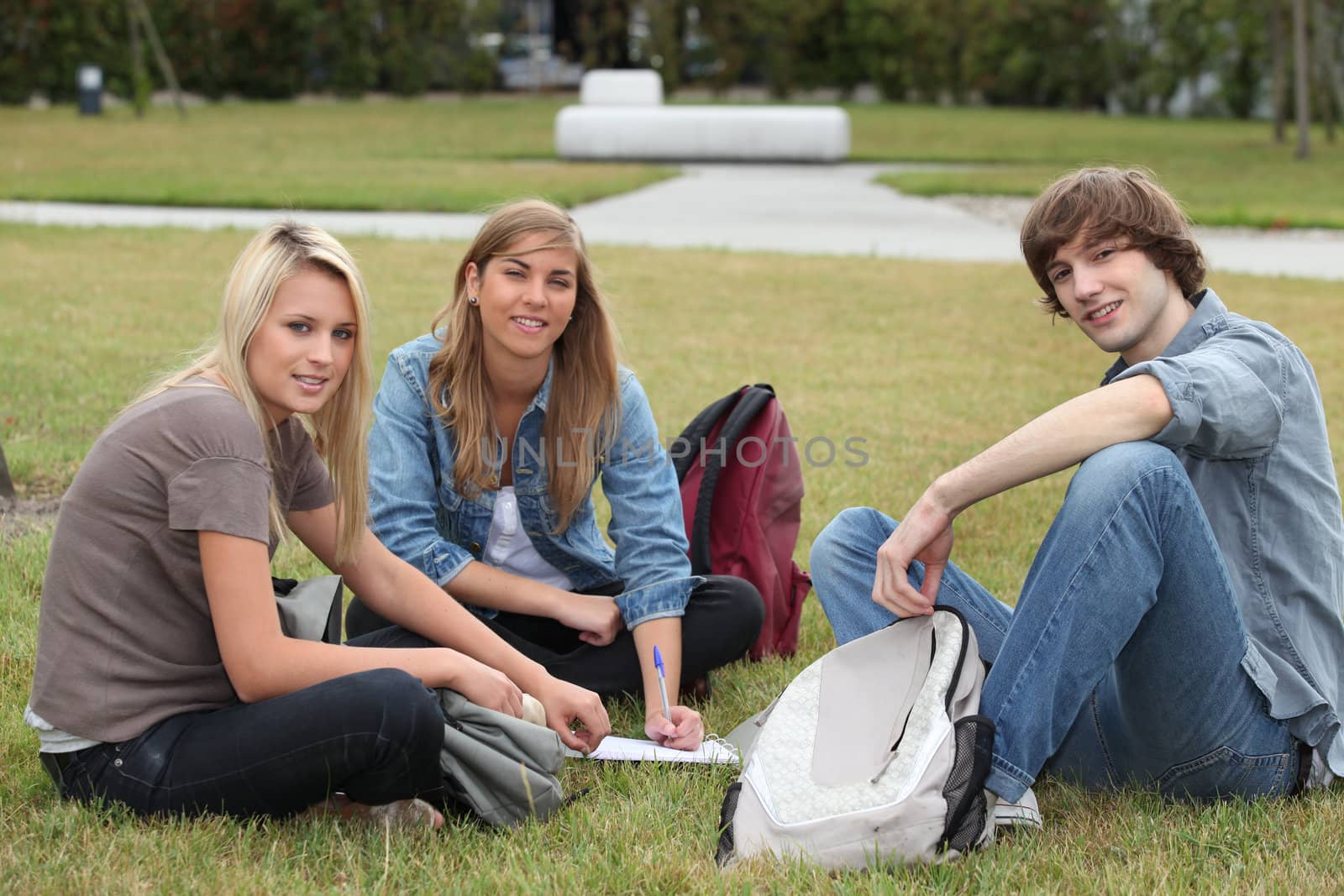 Three students sat in the park working by phovoir