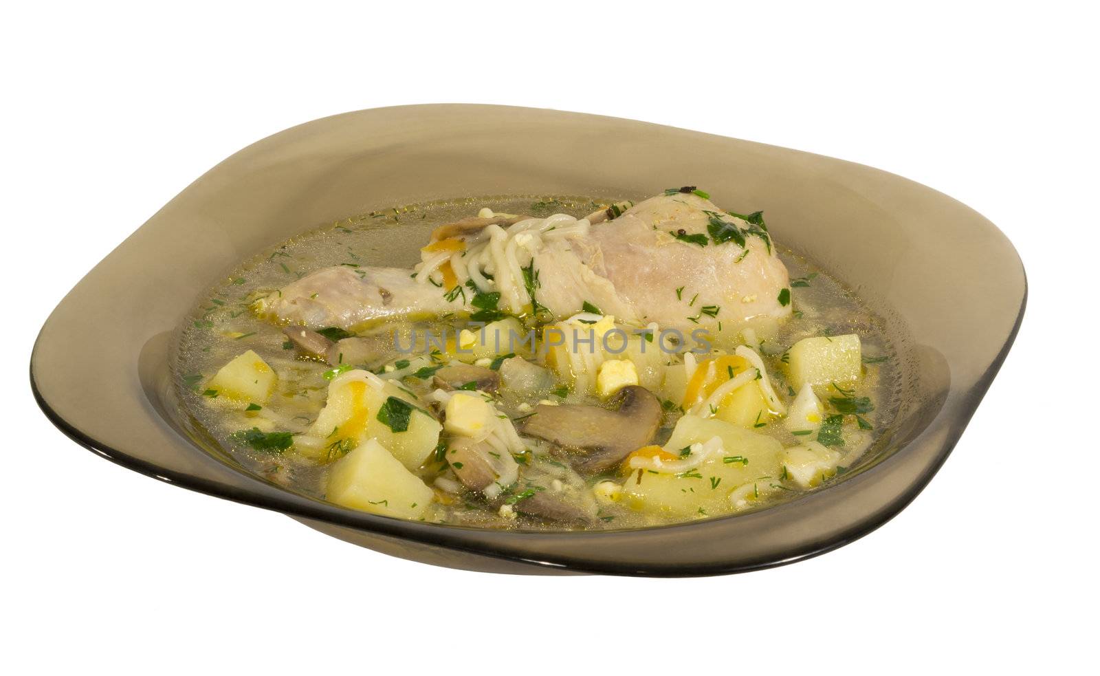 Soup with chicken leg and mushrooms in a dark square plate. Isolated on white background.