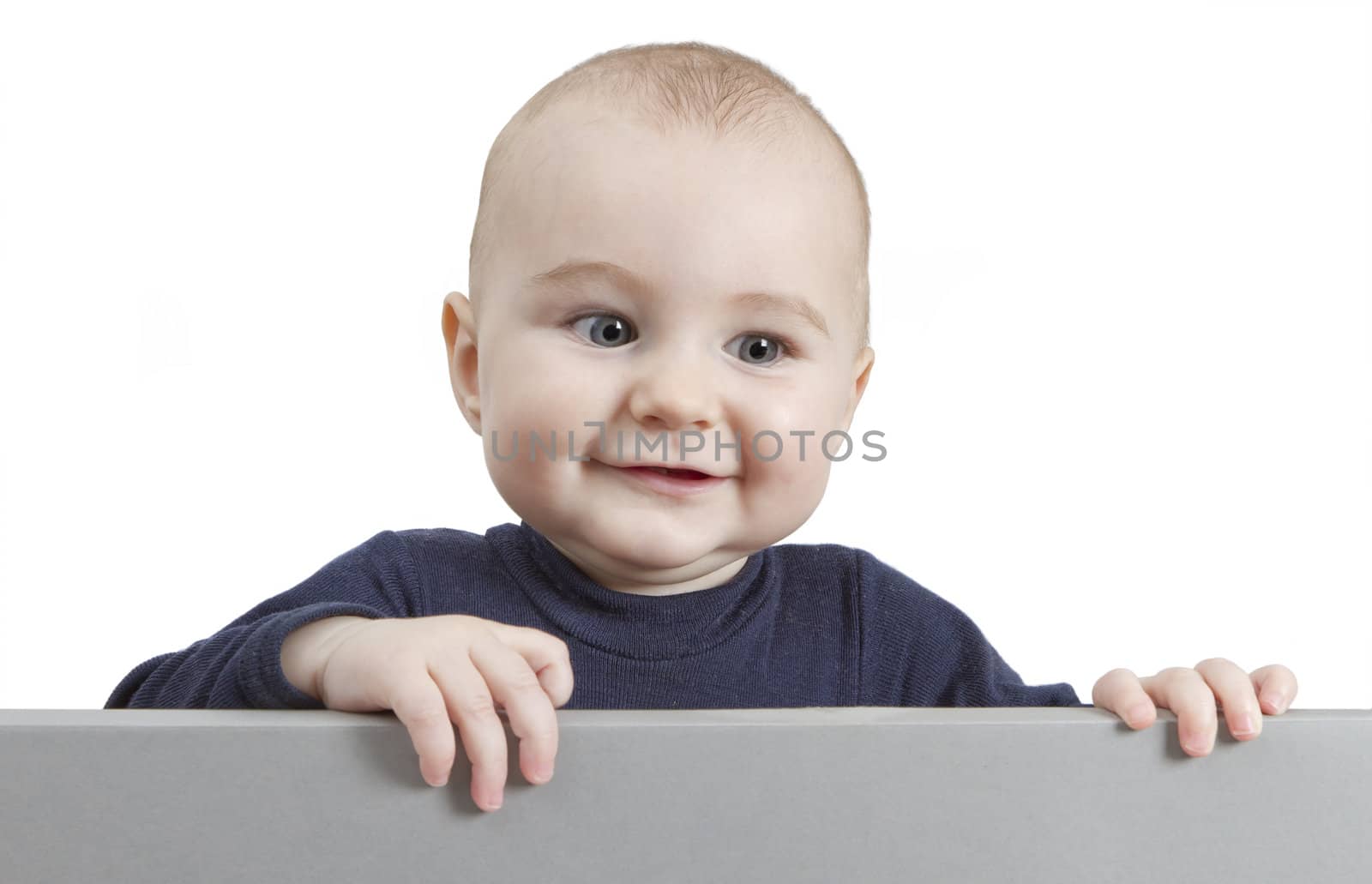 young child standing behind grey cardboard. isolate on white background