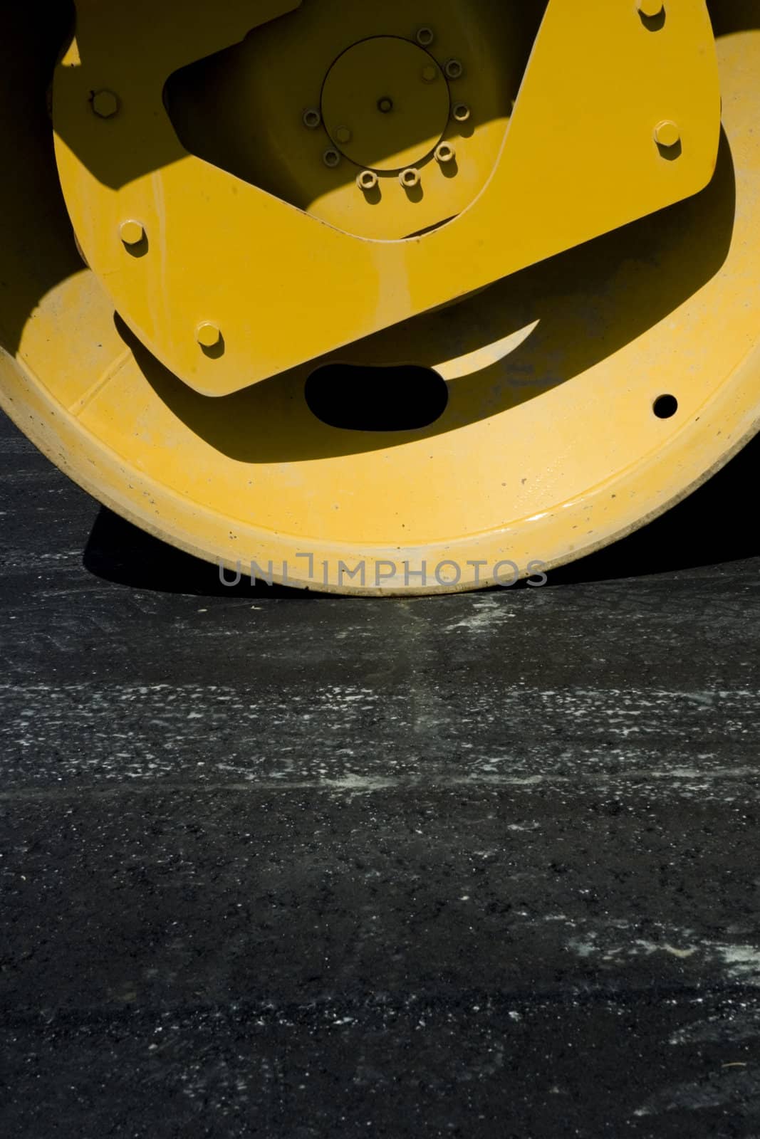 Vertical Closeup of Steamroller with fresh pavement in the foreground