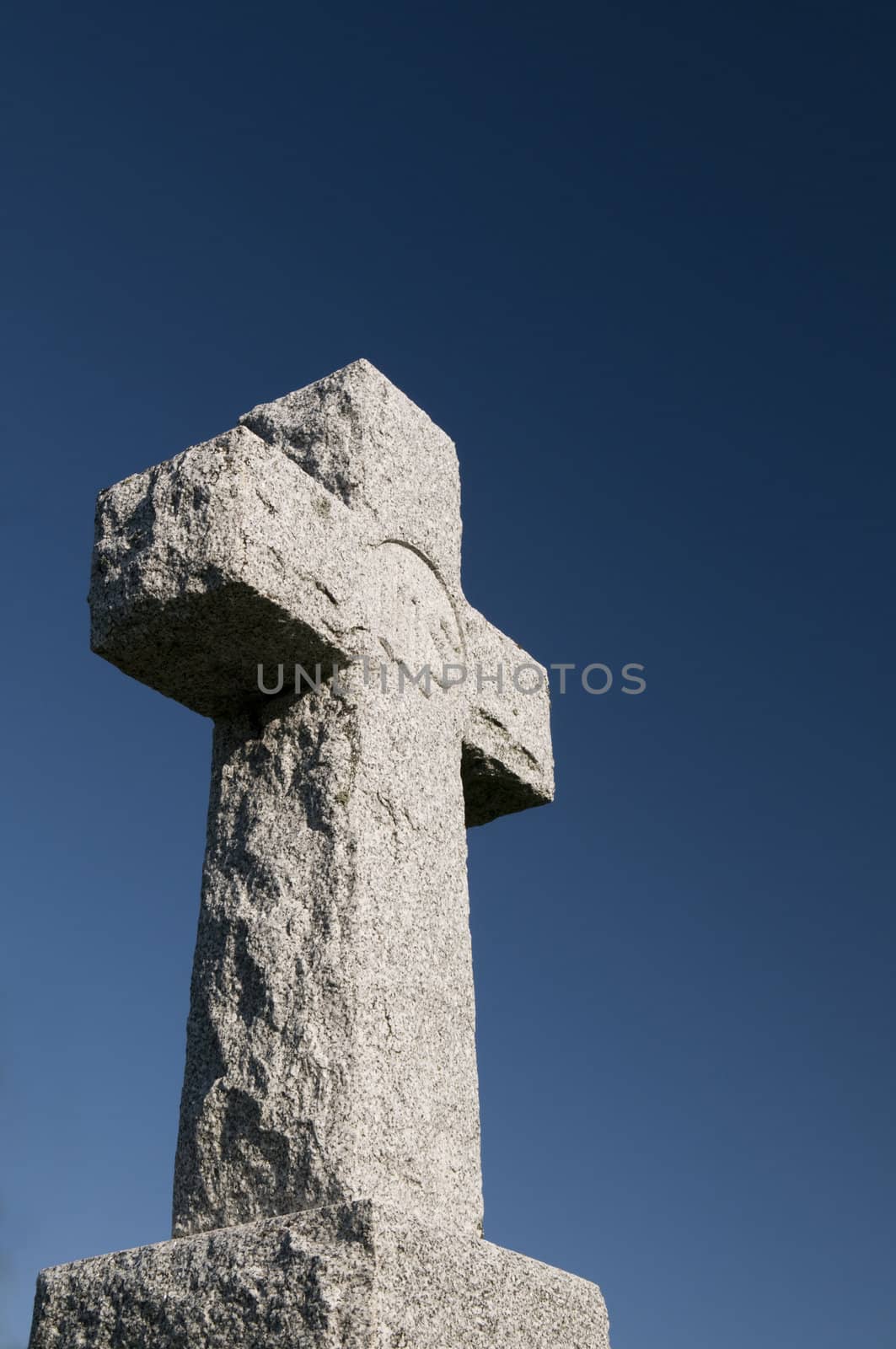 Wide angle image of a stone Christian cross on a deep blue sky
