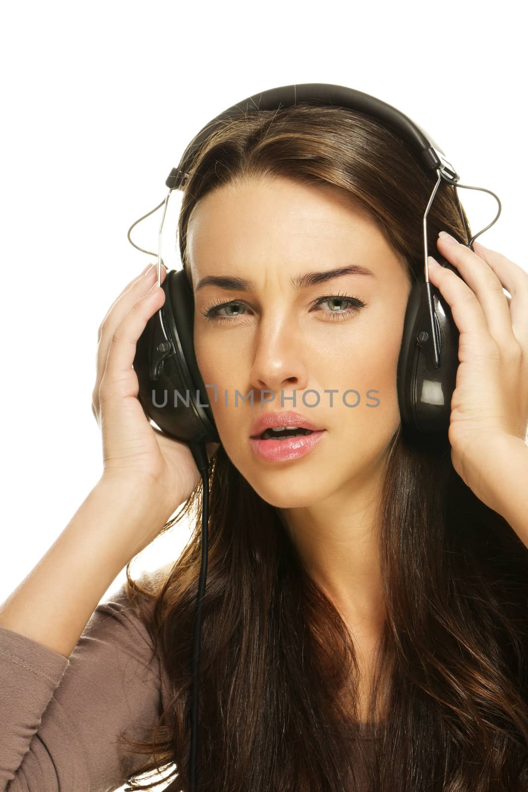 serious looking woman listening to music on white background