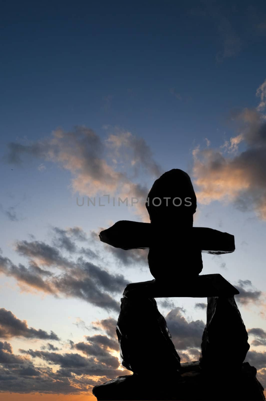 Selective focus on the Inukshuk silhouette in the foreground with sunset in the background