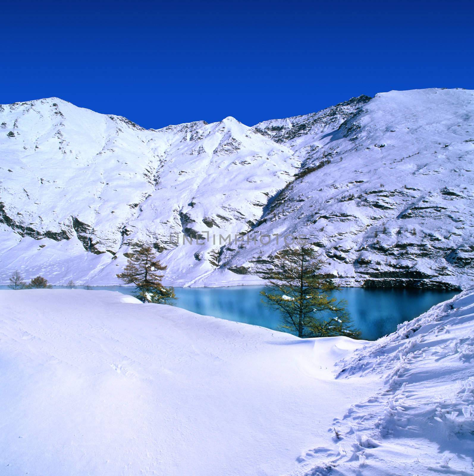 Snow covered mountains with a blue sky and azure lake