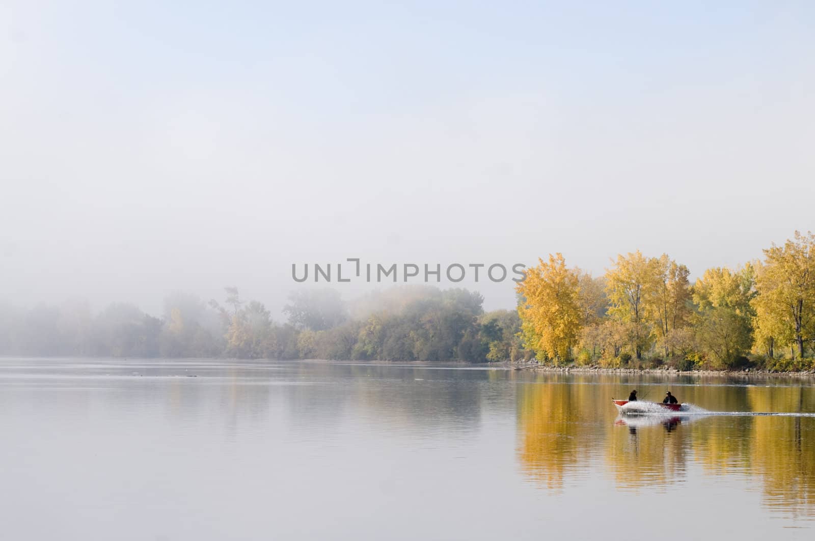 Two fishermen boating on the bay with the fog lifting