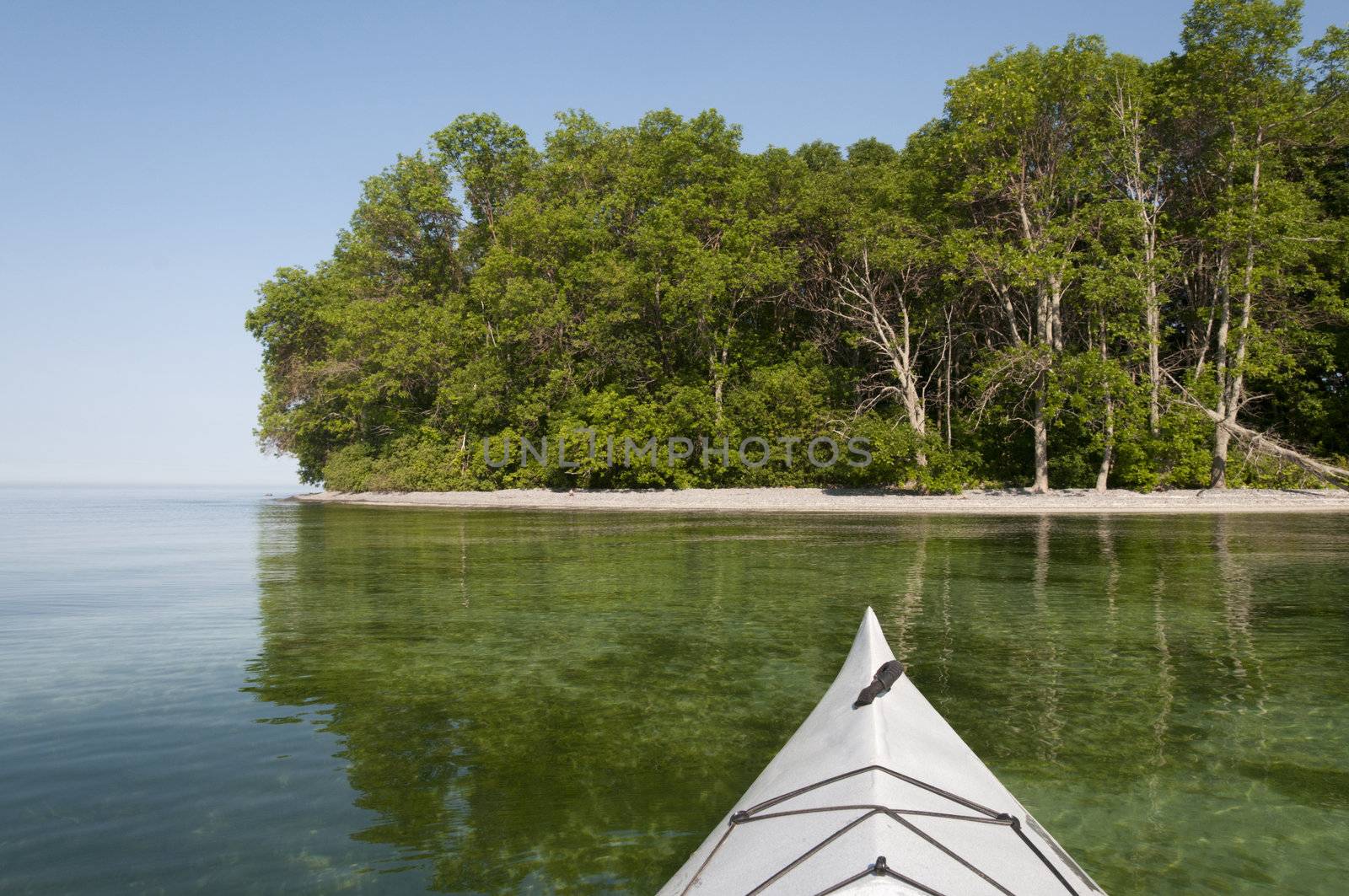 Kayak bow in the foreground on Lake Ontario with the shoreline in the background