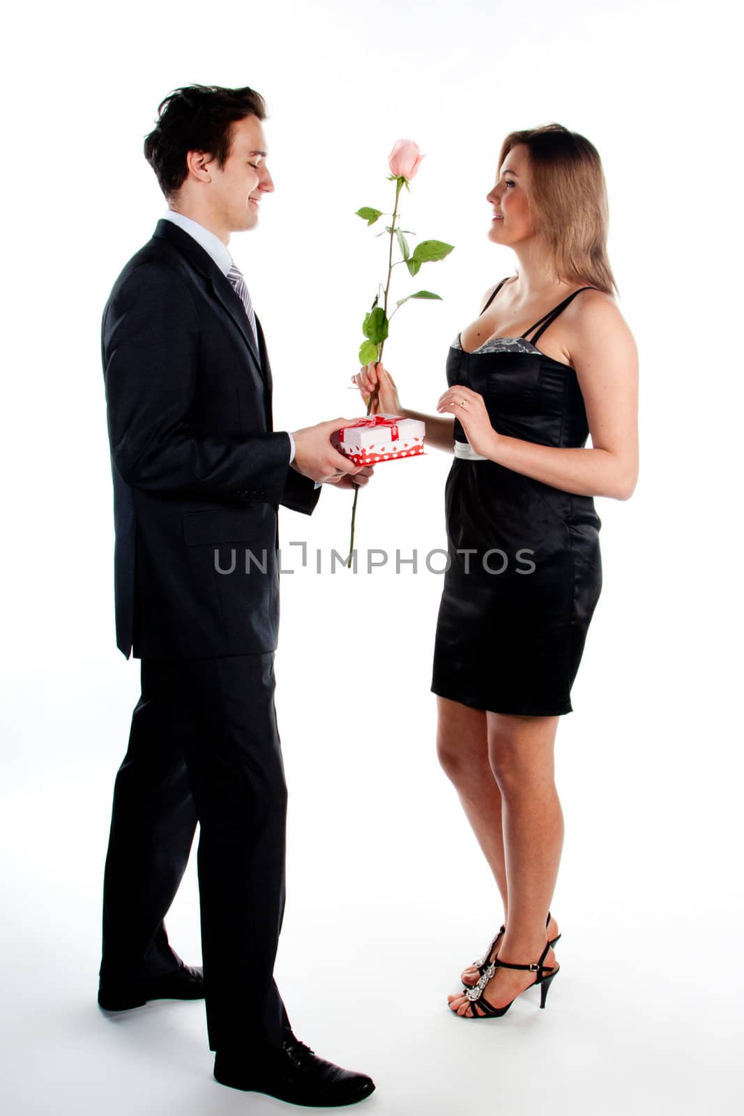 A young man gives a beautiful young woman, a flower in honor of the holiday