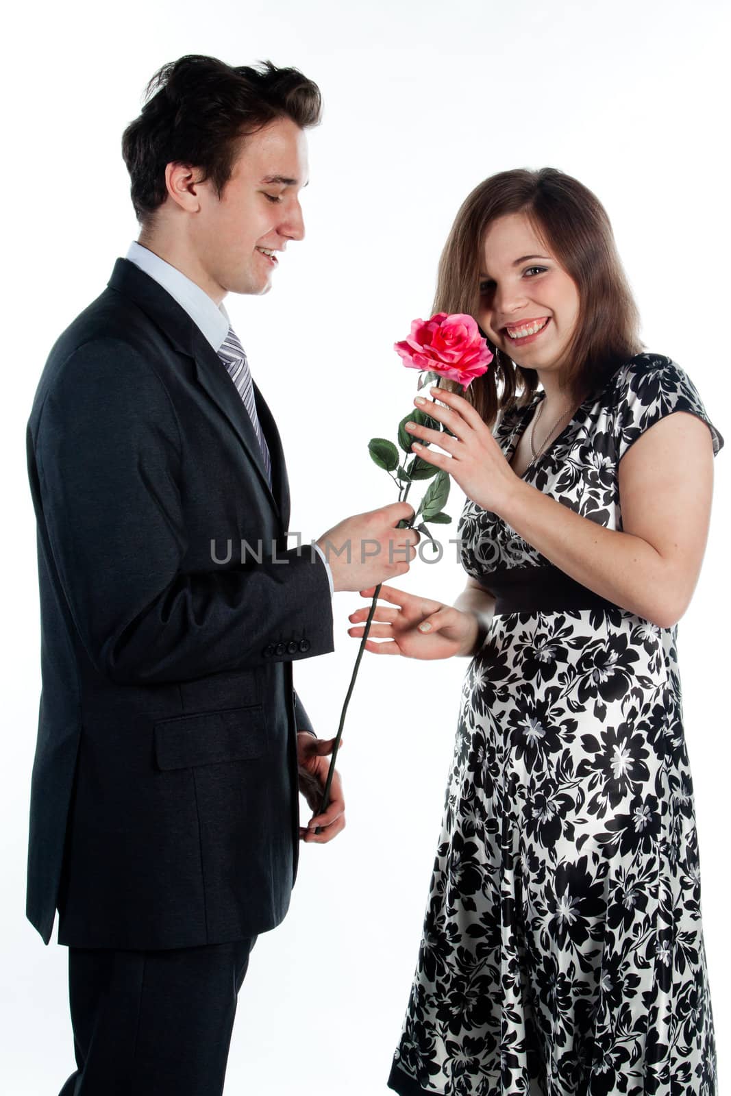 A young man gives a beautiful young woman, a flower in honor of the holiday
