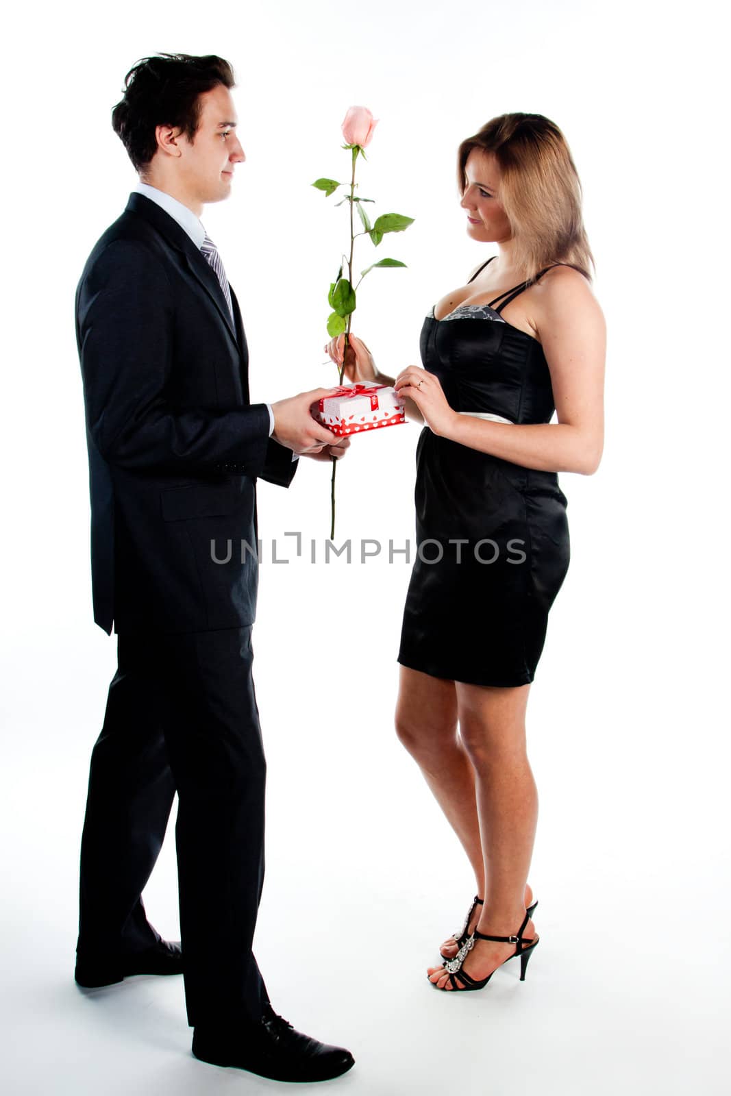 A young man gives a beautiful young woman, a flower in honor of the holiday