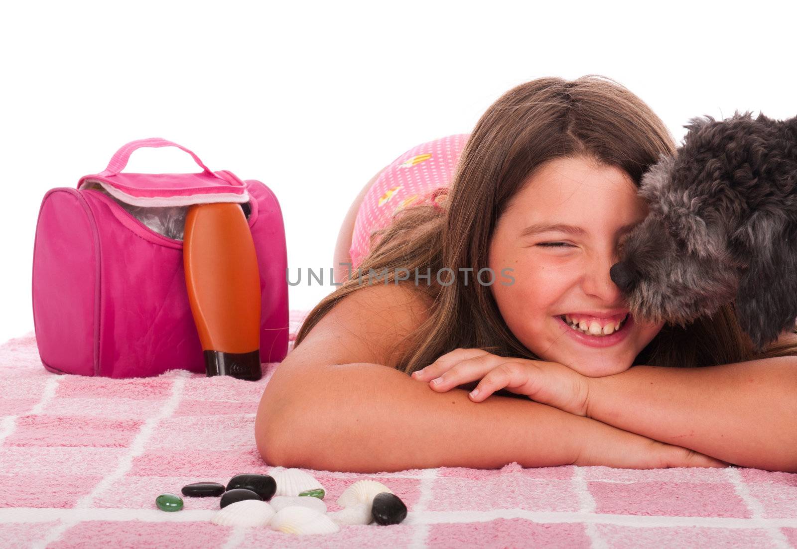 smiling brunette teenage girl in swimsuit at the beach getting a kiss from her shipoo dog (studio setting with beach and personal items) isolated on white background