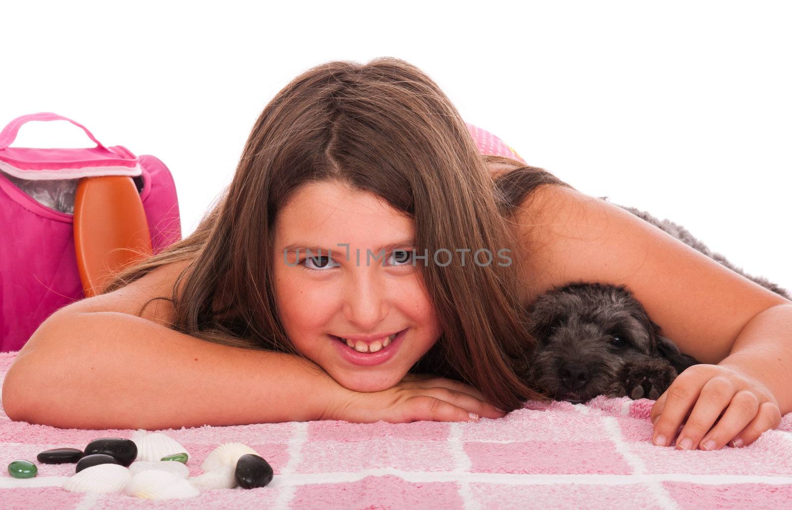 smiling brunette teenage girl in swimsuit at the beach with her shipoo dog (studio setting with beach and personal items) isolated on white background