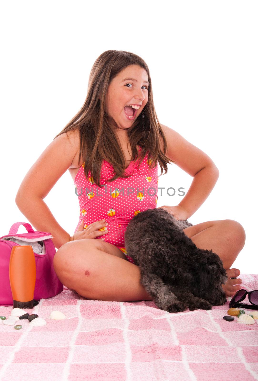 smiling brunette teenage girl in swimsuit at the beach with her shipoo dog (studio setting with beach and personal items) isolated on white background