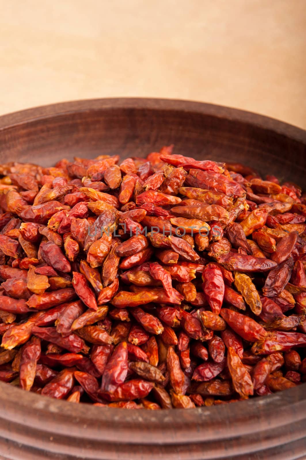 Piri Piri peppers on a vintage wooden bowl (close-up, brown background)