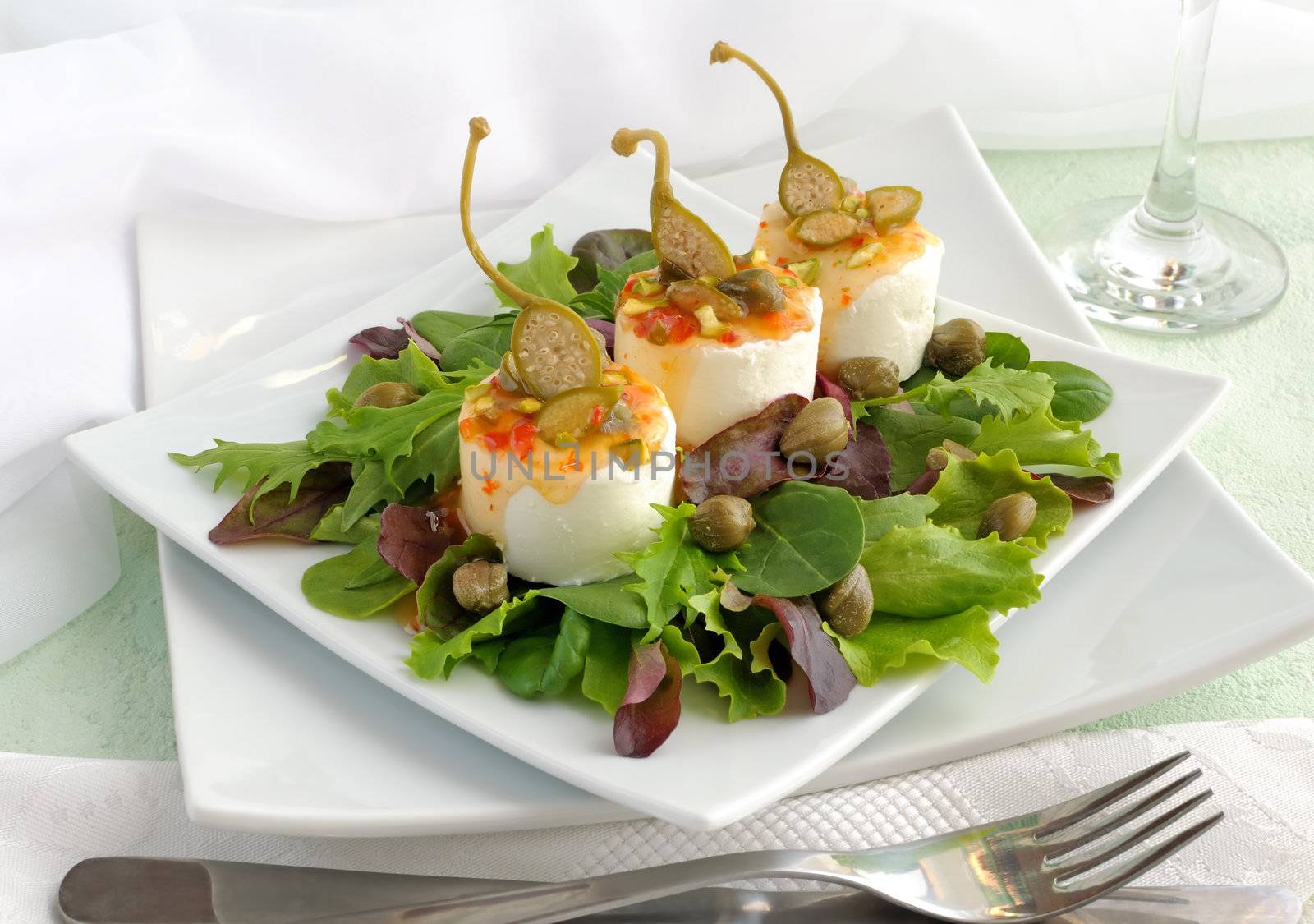 Cheese and capers sweet and sour sauce and pistachios in green leaves