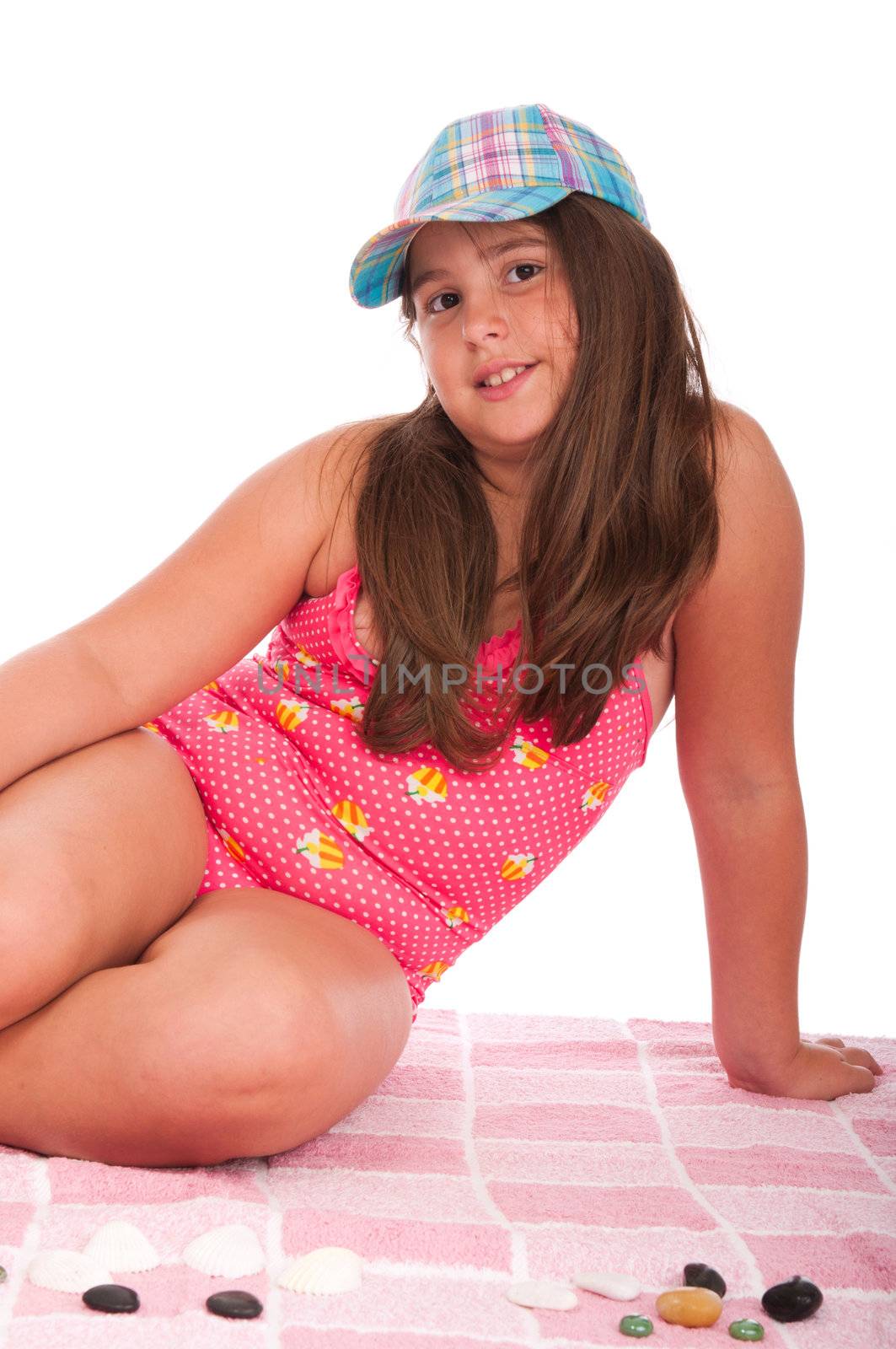 beautiful brunette teenage girl in swimsuit at the beach (studio setting with towel and pebbles, isolated on white background)