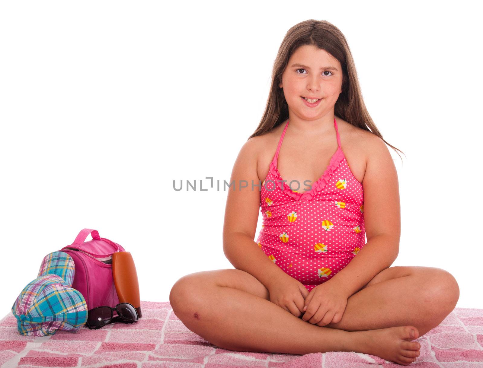 beautiful brunette teenage girl in swimsuit at the beach (studio setting with bag, cap, towel, sun lotion, sunglasses) isolated on white background