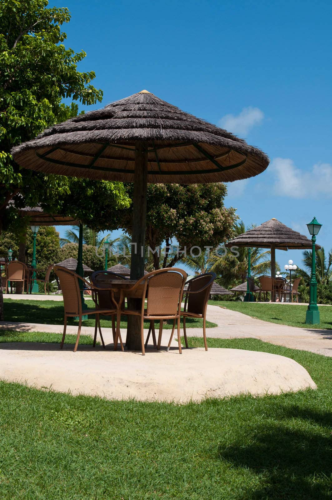 straw umbrella and chairs in a tropical resort (next to the swimming pool)