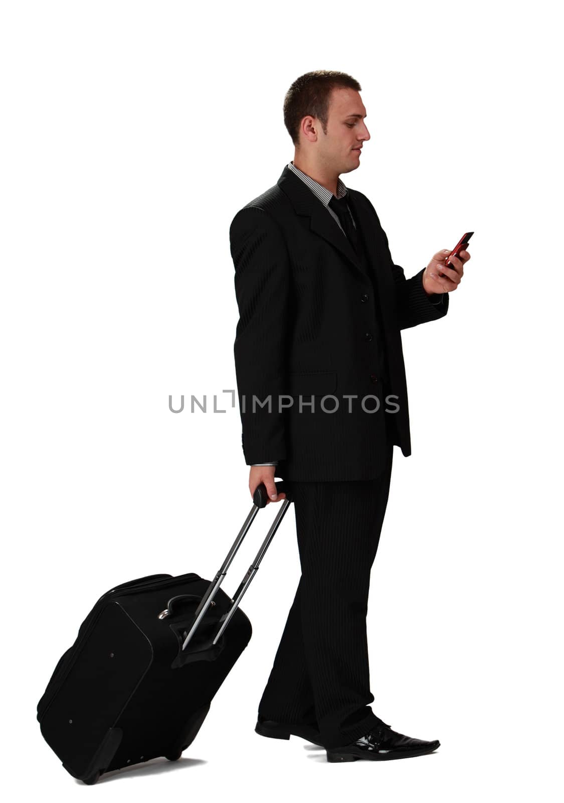 Young businessman with a suitcase reading a phone message against a white background.