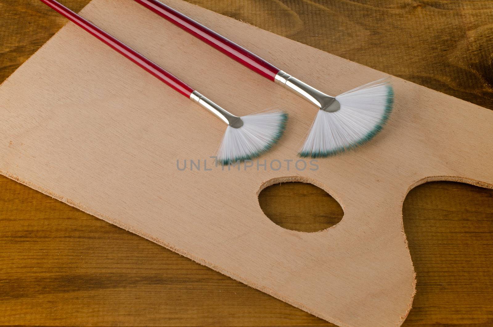 Painting brushes and art pallete on wooden board.