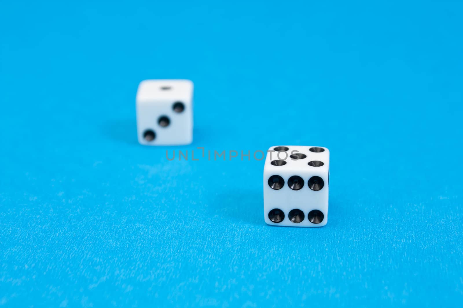 Closeup photo of white standard dices on blue background.