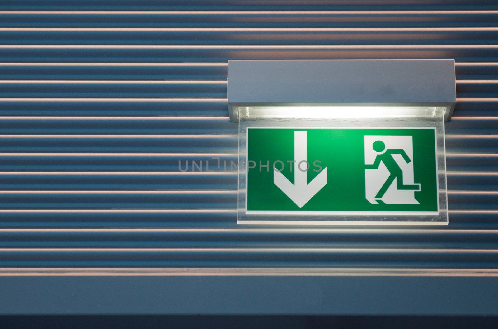 illuminated green emergency exit sign on a modern wall  