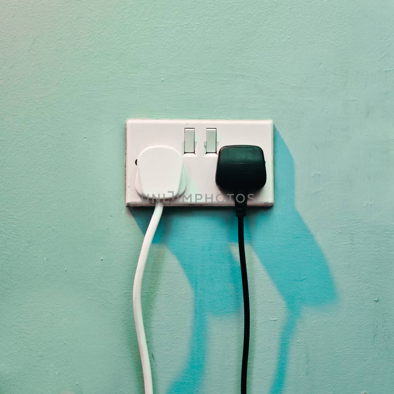 Black and white electric plugs in a wall socket