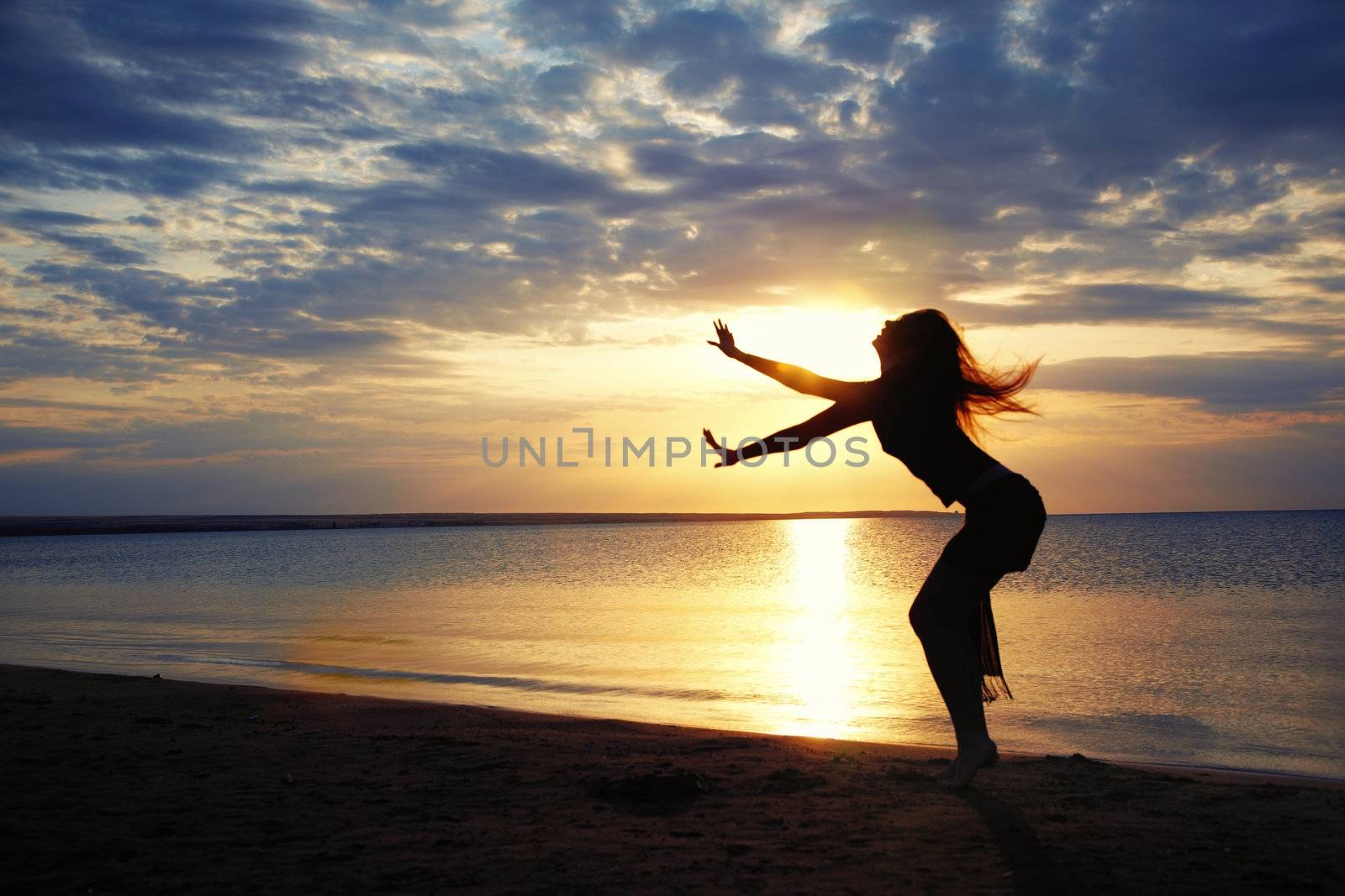 Active woman dancing at the beach during sunset