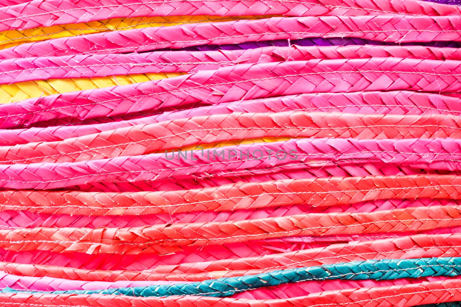 Close up of a stack of colorful straw hats as a a background