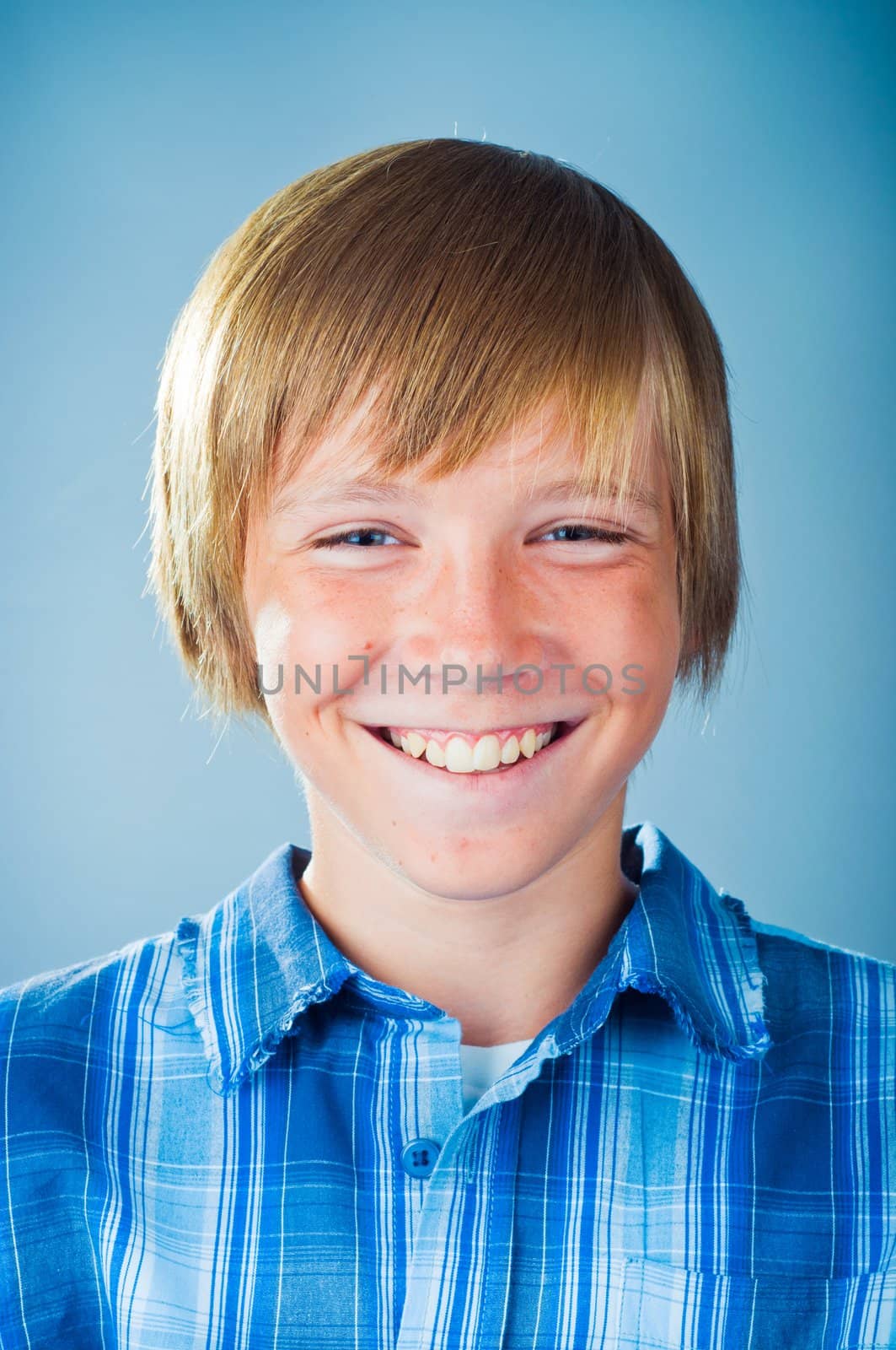 portrait of a smile teenager looking up, on a blue background.