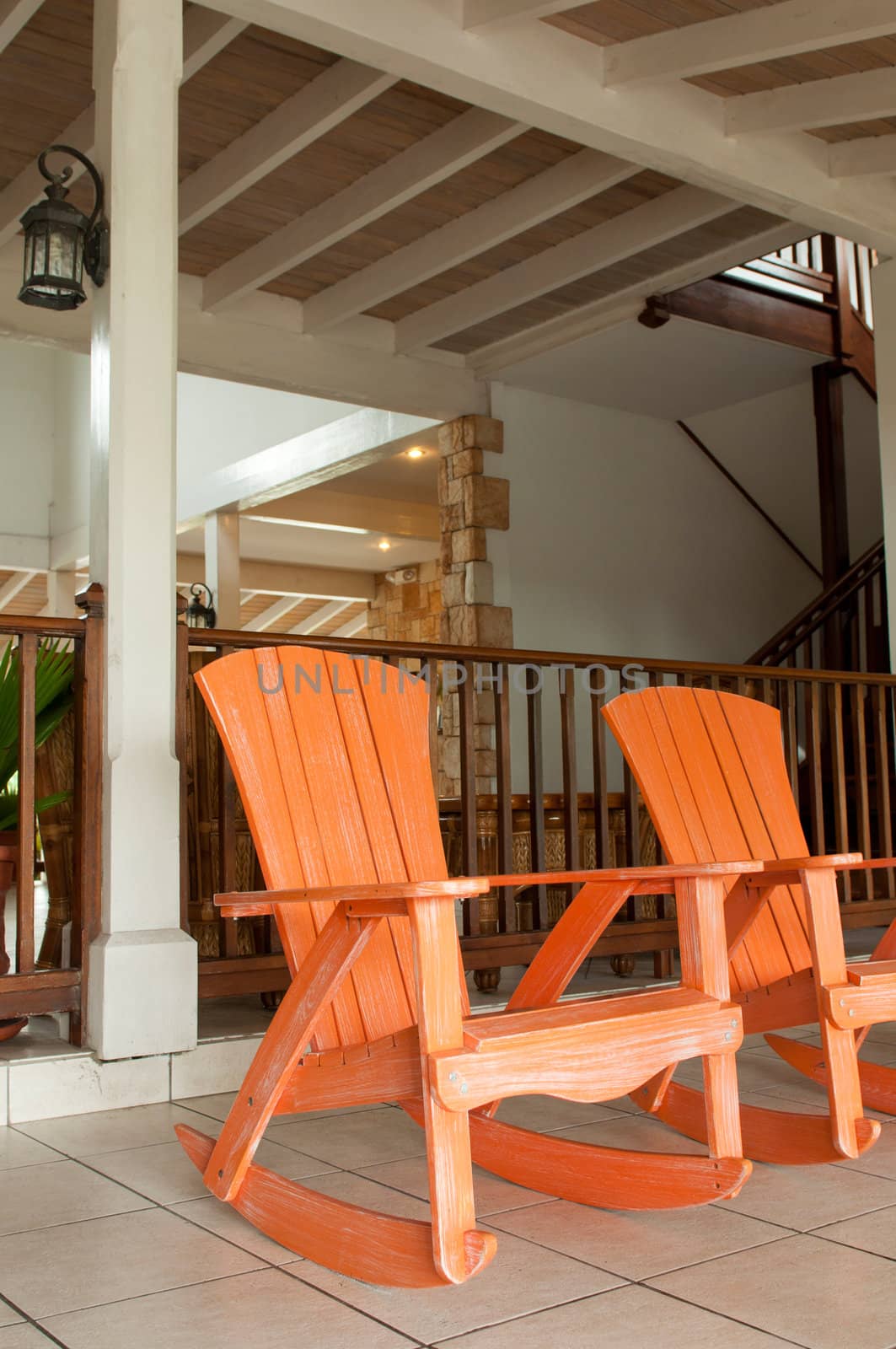 orange wooden rocking chairs on a porch (usual setting on a tropical resort)