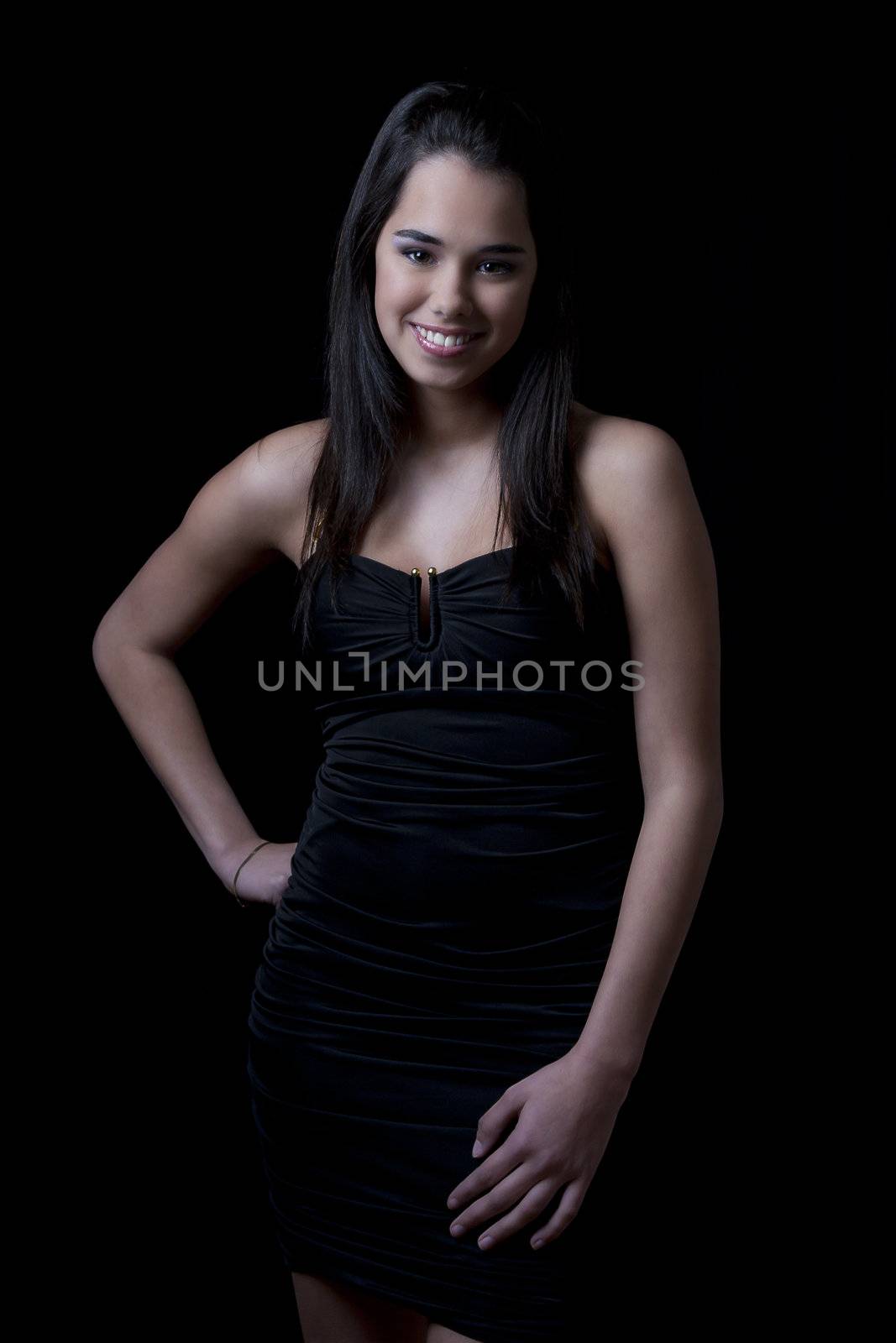 Young woman wearing a little black dress against a black background