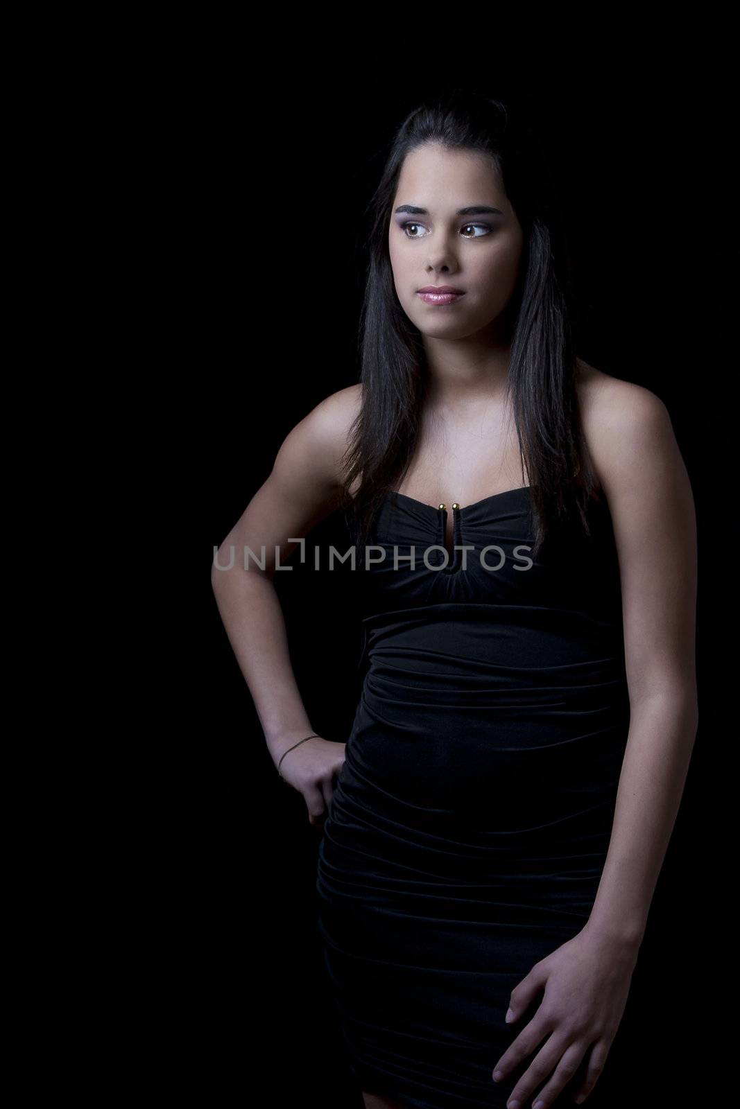 Young woman wearing a little black dress against a black background