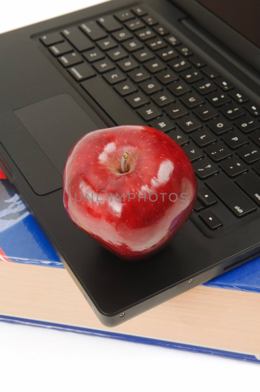 Closeup on a school book, laptop and red apple
