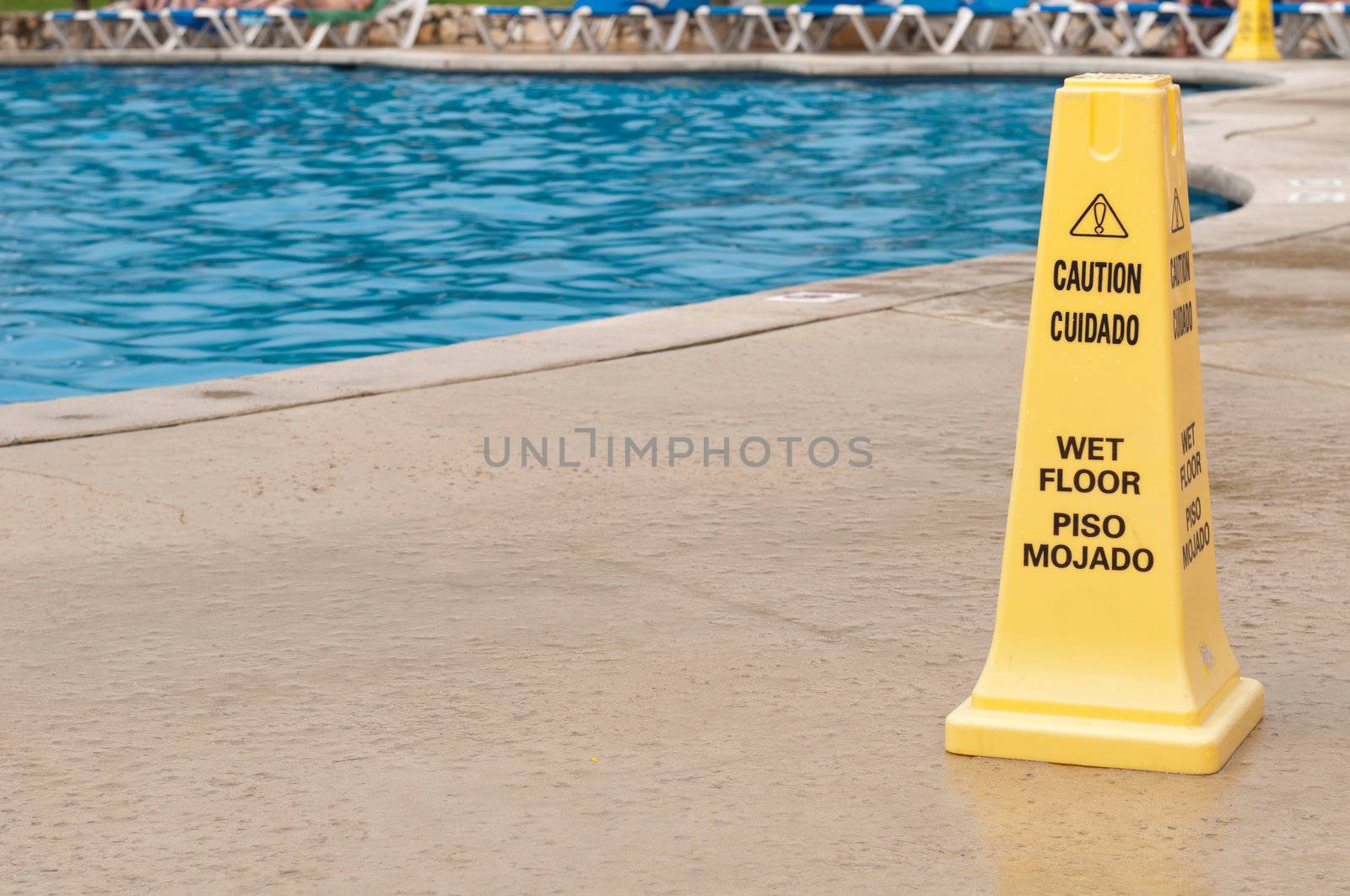 yellow caution sign regarding slippery surface next to a swimming pool (after a tropical storm)