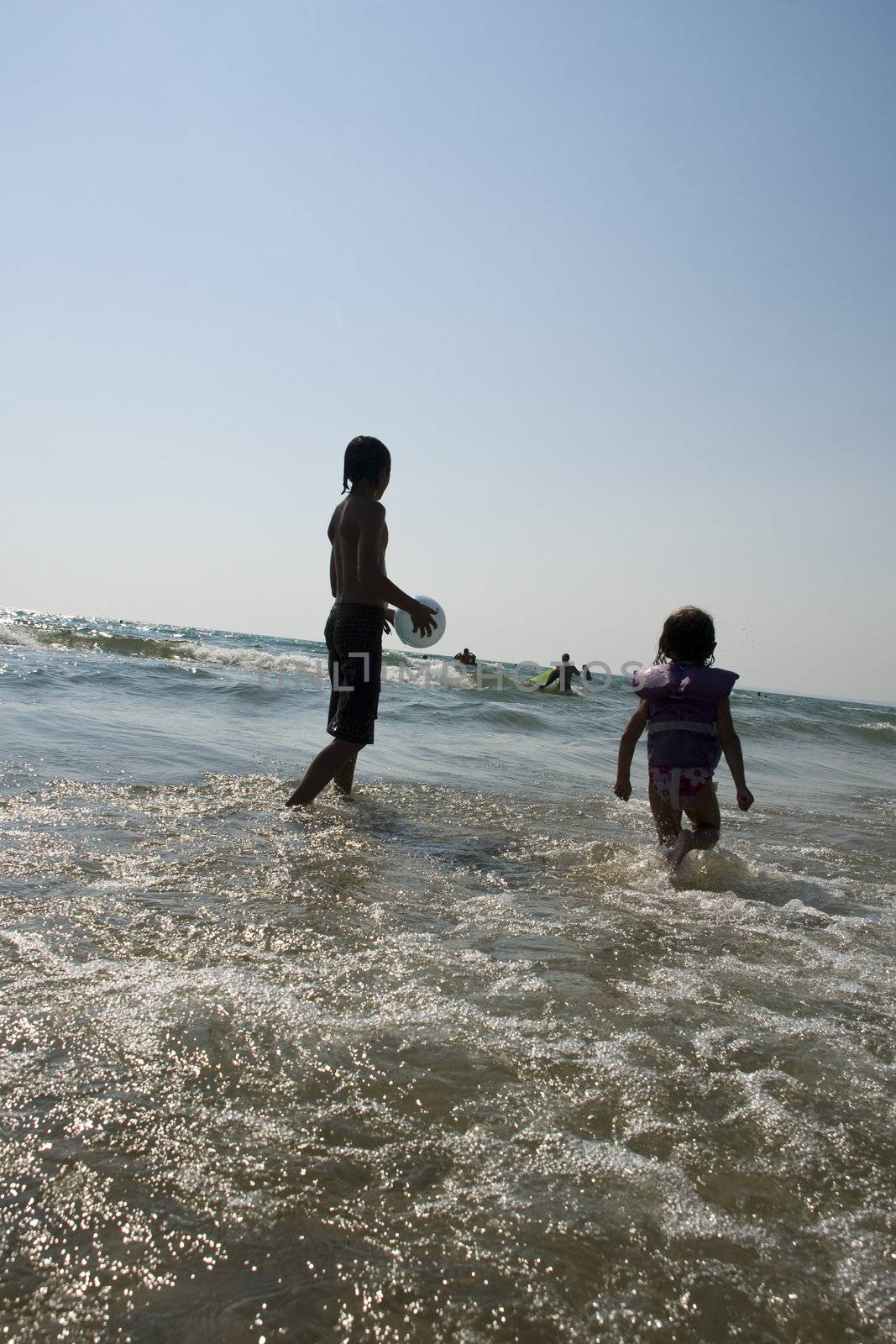 Brother and sister enjoy the waves at the beach.