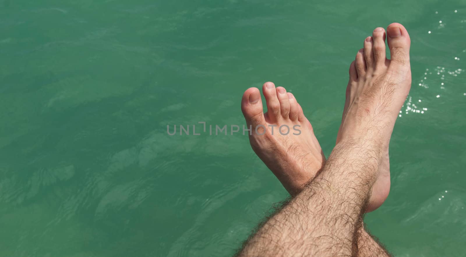 relaxing feet on lake during a hot sunny day (summer vacations concept)